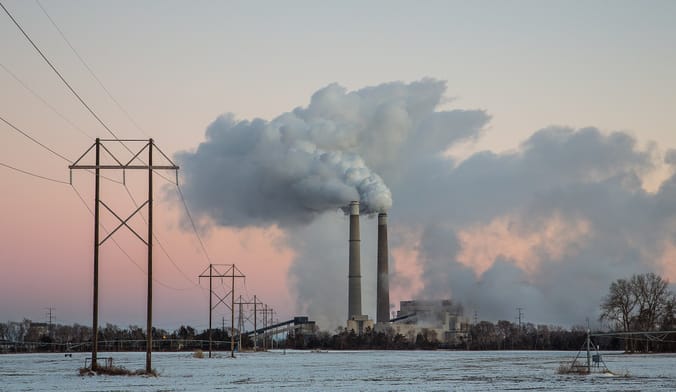 coal power plant with smokestacks against snowy scene