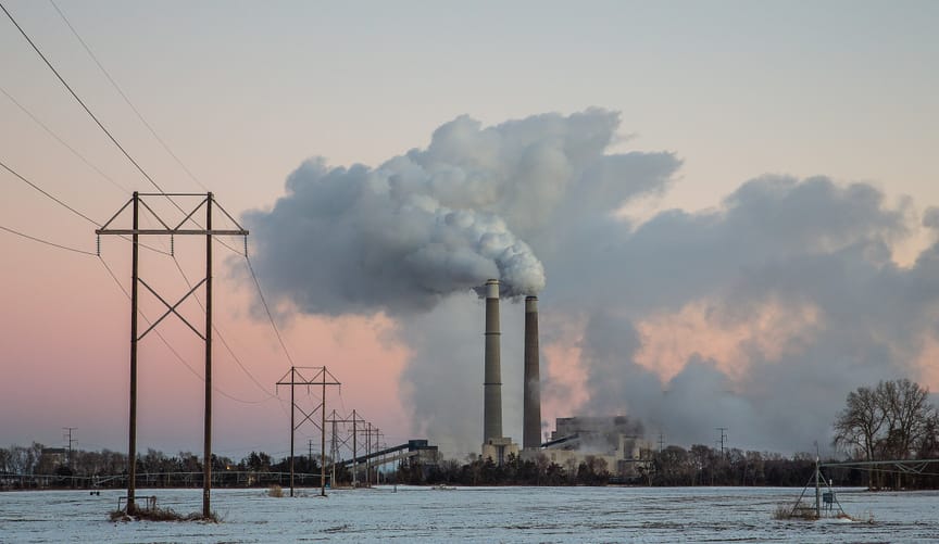 coal power plant with smokestacks against snowy scene