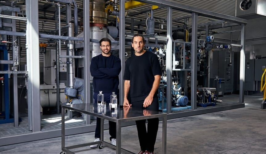 Two men wearing black clothes stand in an industrial facility