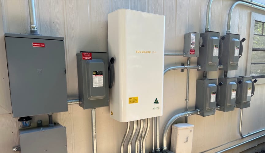 An Allume Energy SolShare unit installed between an apartment building rooftop solar inverter and individual apartment meters