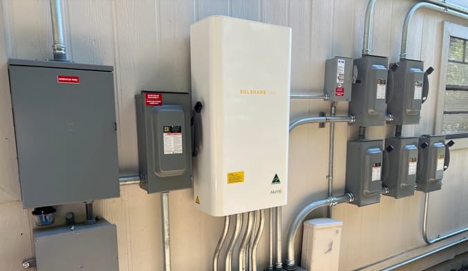An Allume Energy SolShare unit installed between an apartment building rooftop solar inverter and individual apartment meters