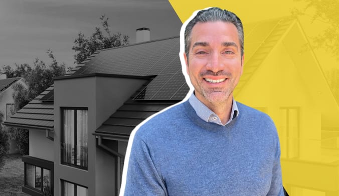 A smiling man with gray hair in a blue sweater in front of a stylized graphic of a house