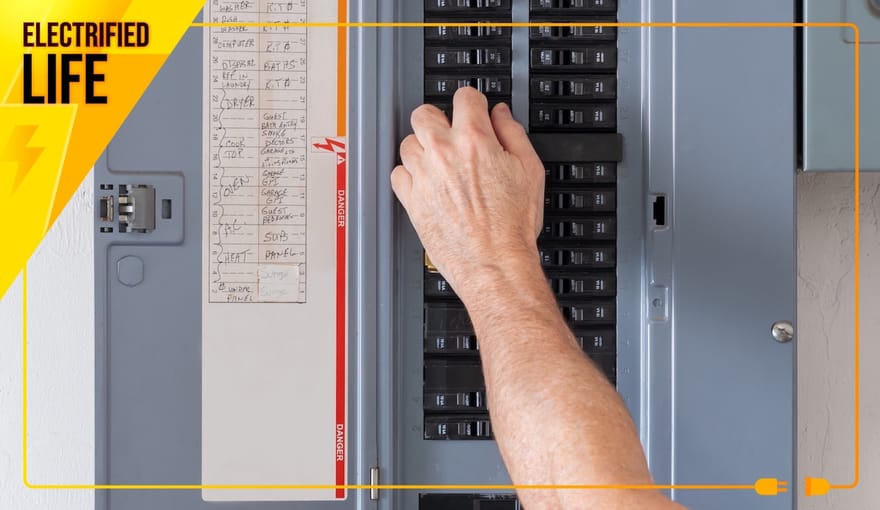 A person's arm reaches out to a circuit breaker inside of they gray metal box of an electrical panel.