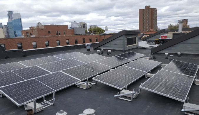A rooftop solar array on a roof in a city skyscape