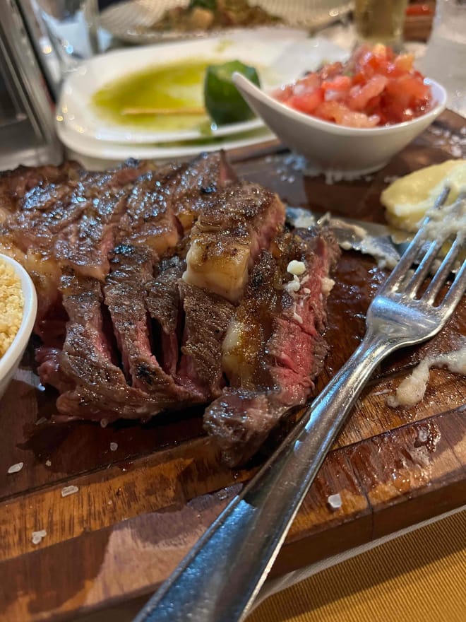 A closeup of a dinner plate with sliced rare steak next to a fork