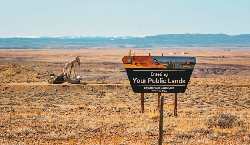 Bureau of Land Management Sign on a field with pumpjack in the background