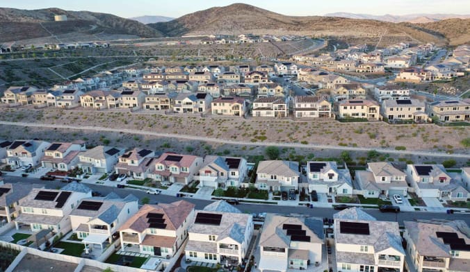 An aerial view of homes in a housing development with new houses under construction and solar panels on roofs
