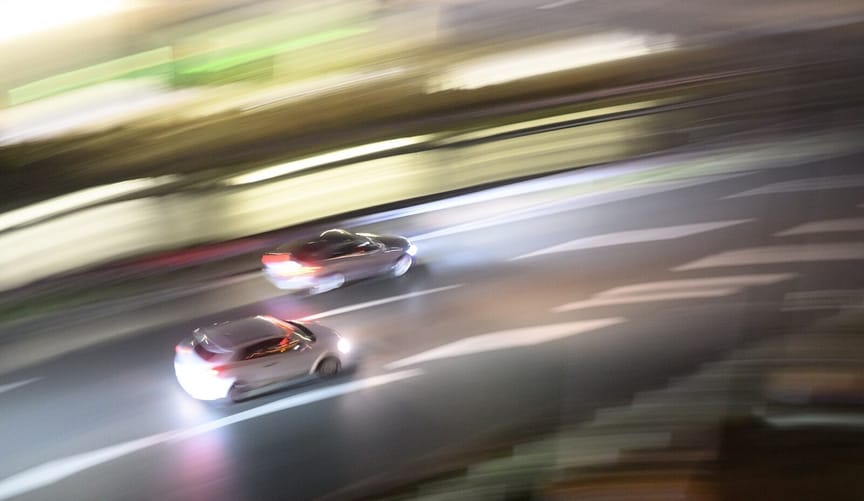 two cars drive along a road