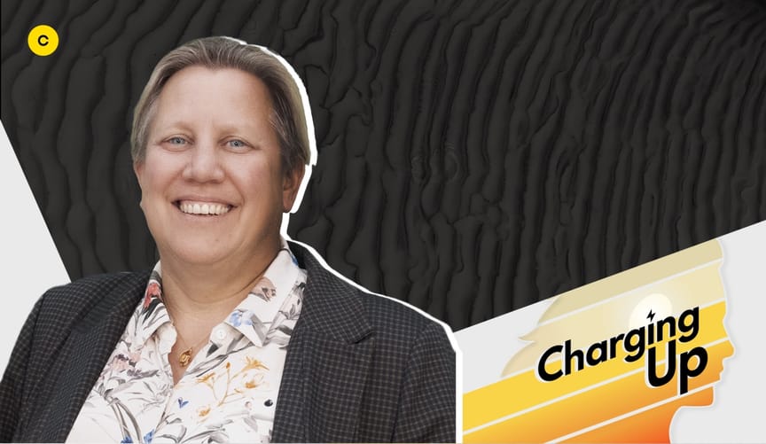 A smiling woman with short light-brown hair and a light skin tone wearing a gray blazer. A graphic overlay reads Charging Up.