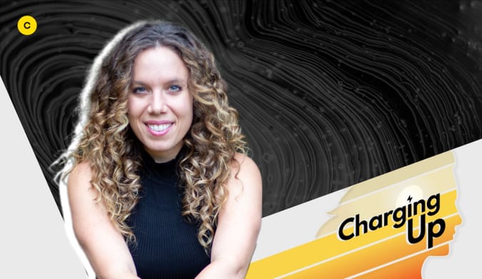 A white woman with curly light brown hair wearing a black shirt next to a stylized graphic that says charging up