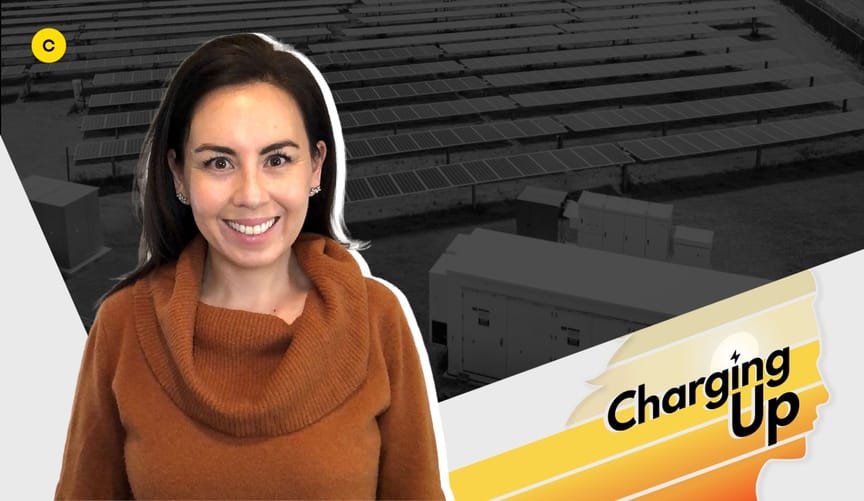 A smiling woman with long dark hair in a rust-colored cowl neck sweater. A stylized graphic has the words "Charging Up"