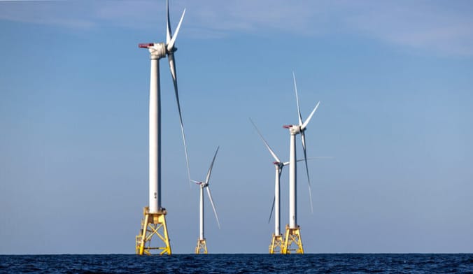 A group of four large white wind turbines in the ocean
