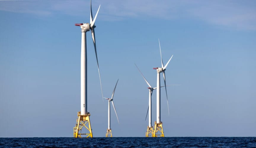 A group of four large white wind turbines in the ocean