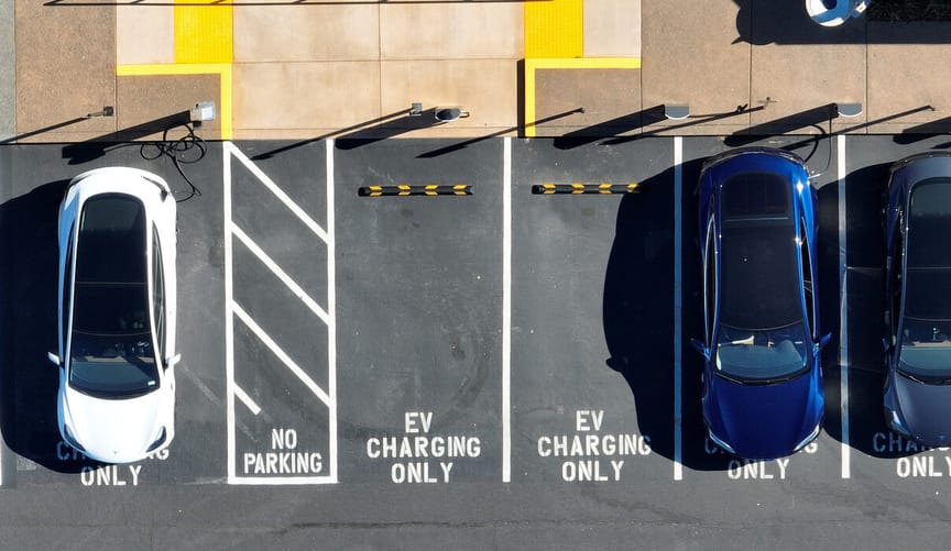 an aerial view of several cars parked in parking spots marked with the words EV CHARGING ONLY