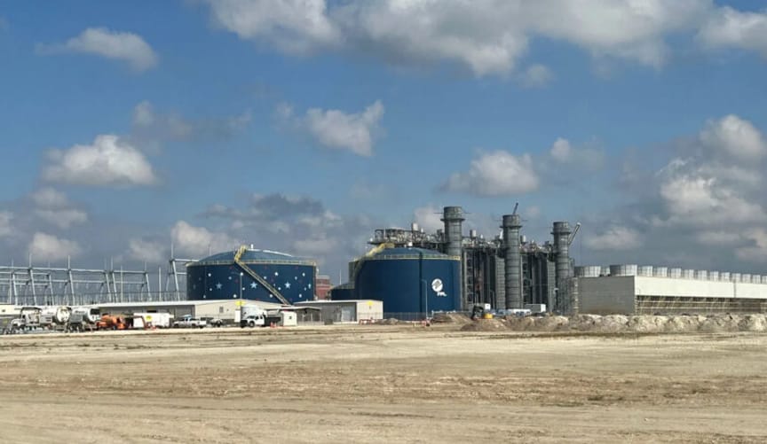 A large industrial facility is shown; in the foreground is a large dirt lot