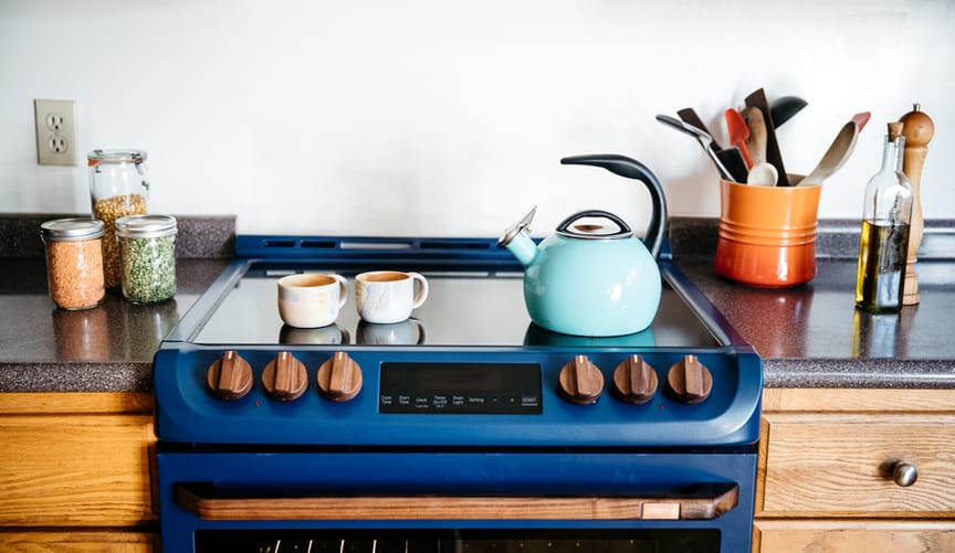 A blue induction range with two mugs and an aqua kettle sitting on top
