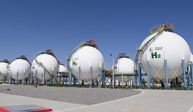 Several rows of large spherical white metal tanks stamped with a green H2 sign