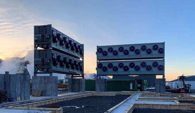 Two very large industrial devices outdoors surrounded by plumes of steam