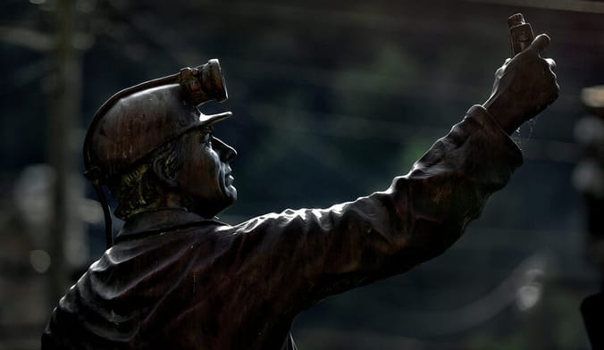 A bronze statue of a coal miner is seen in profile