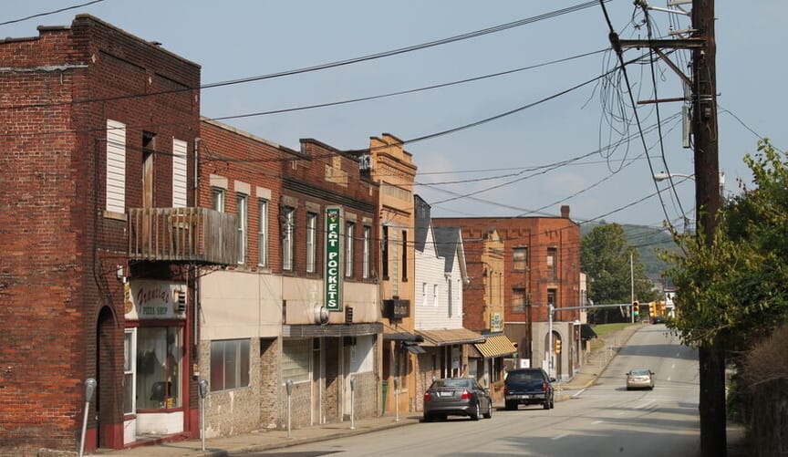 a deserted street flanked on the left side by dilapidated old two story red brick buildings