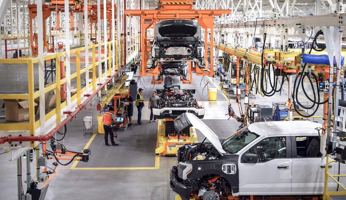 workers assemble vehicles on an assembly line in a large factory