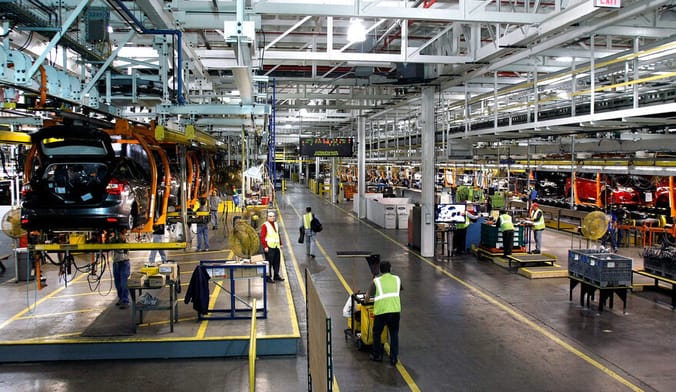 Workers mill about performing various tasks inside a large factory