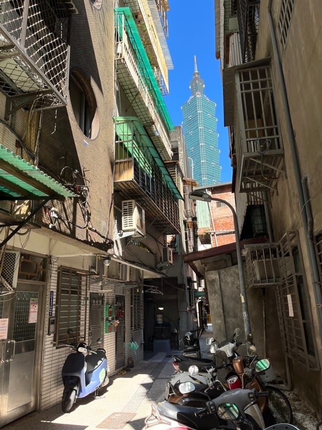 An alley with multistory buildings on both sides, some with heat pumps