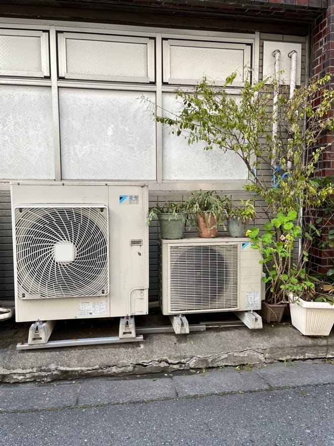Two smaller heat pump units surrounded by potted plants