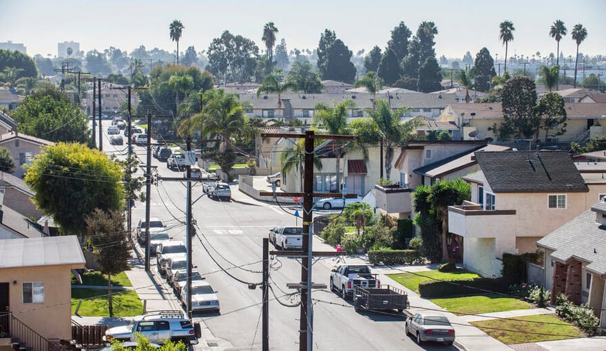 An aerial view of a middle-class neighborhood in California with palm trees seen in the distance
