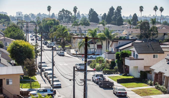 An aerial view of a middle-class neighborhood in California with palm trees seen in the distance