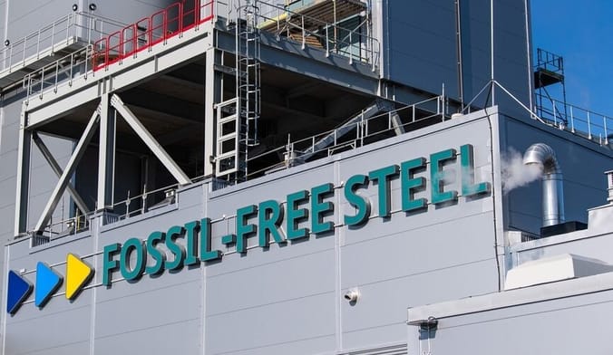 A close-up of the facade of a factory bearing the words "FOSSIL-FREE STEEL"