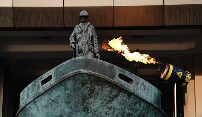 A flaming device is pointed at a puppet oil tanker