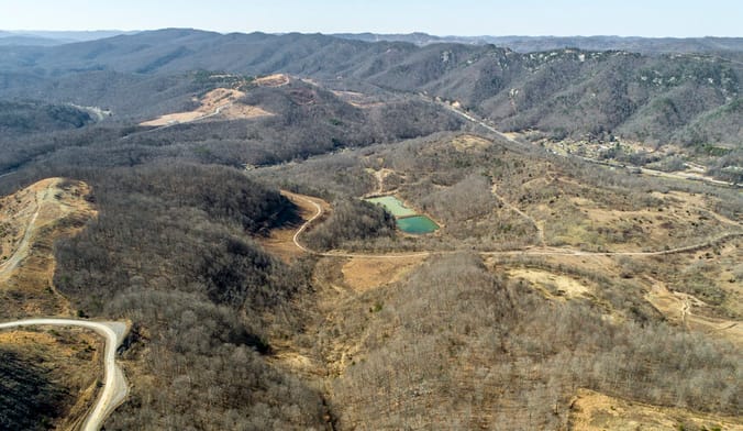 an aerial photo of a forested mountain valley with a blue body of water at the center