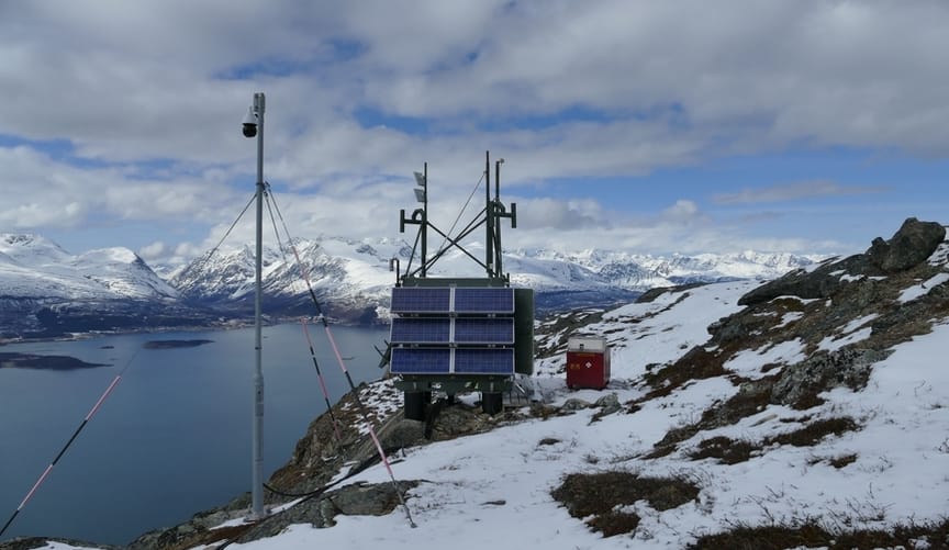 Several pieces of equipment are set up on a ledge in a snowy mountain range