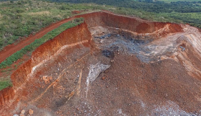 a large open pit mine surrounded by a forested hillside