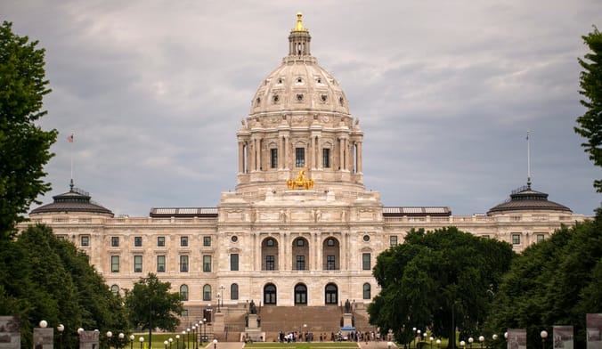A large white neoclassical-style government building with a golden cupola surrounded by trees