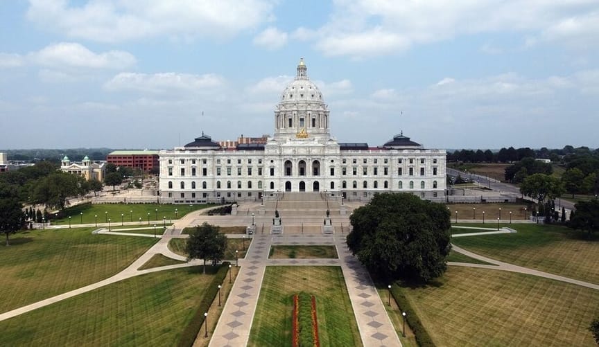 A large white building with a dome in a grassy parklike field