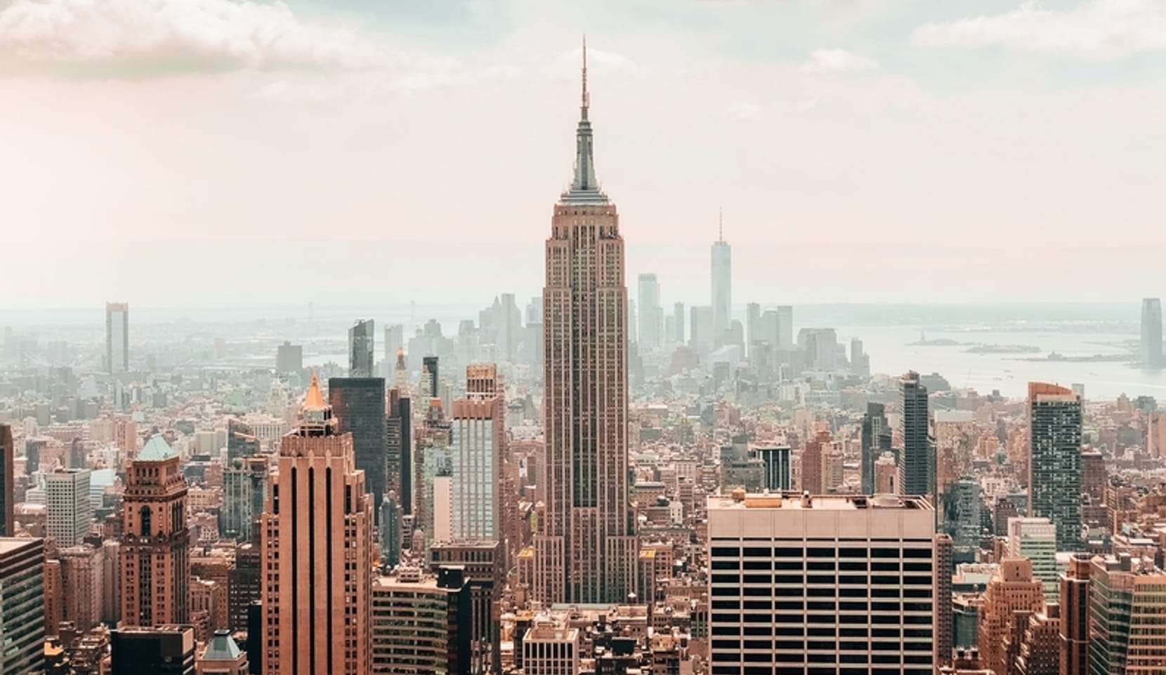 An aerial view of the Manhattan skyline with the Empire State Building in the center of the frame