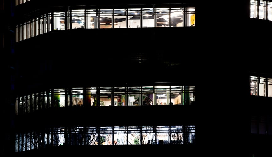 An office building is seen at night with its windows illuminated