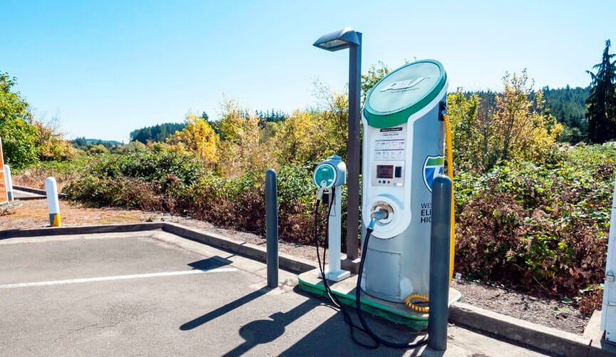 An EV charger in a parking lot in a rural wooded area