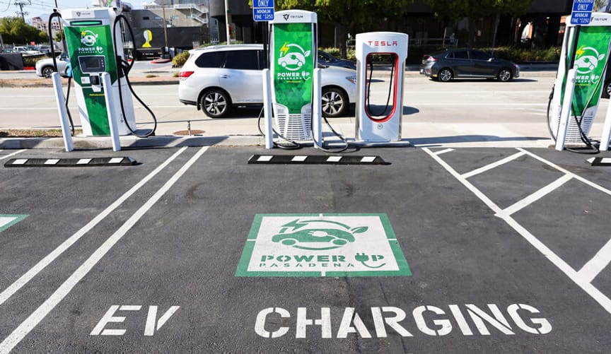 A public parking spot with the words EV charging only and two different types of EV chargers