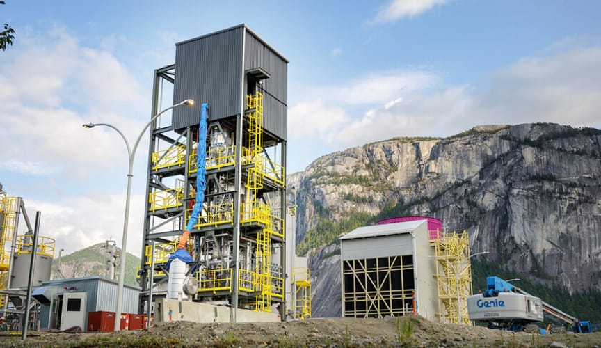 A multistory industrial facility in front of a rocky mountain