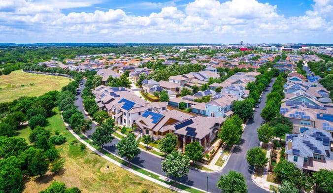 An aerial view of a large subdivision with many houses that have solar panels installed on their roofs
