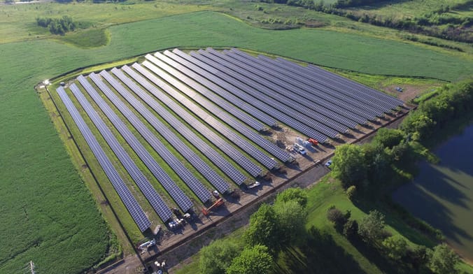 a solar array in a field surrounded by grass and trees