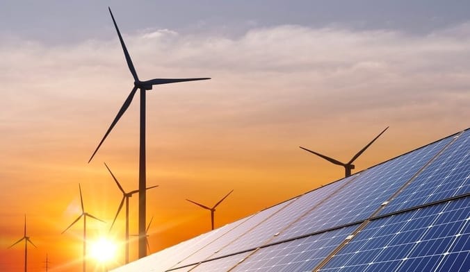 Wind turbines and solar panels against the backdrop of an orange sunset