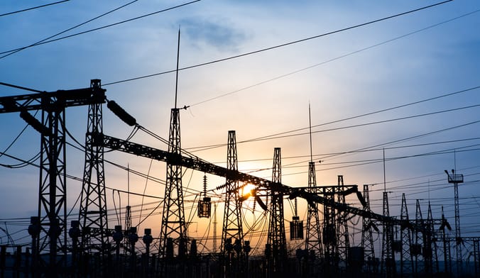 the silhouette of a power substation at sunset