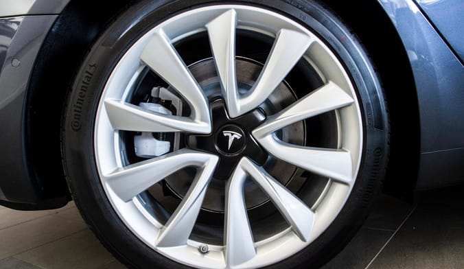 A close-up shot of a tesla wheel and tire with the T-shaped Tesla logo visible at center