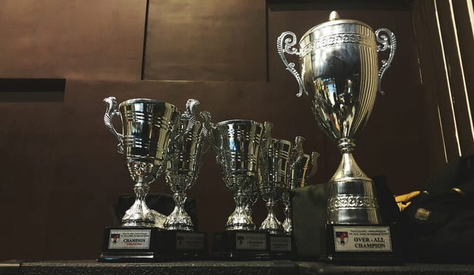 A group of gold trophies sitting on a shelf