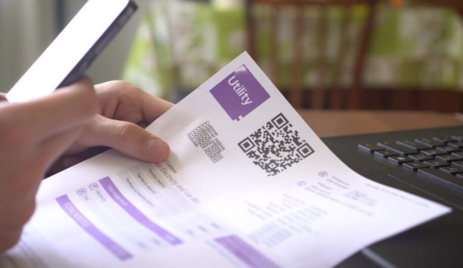 A person's hand holding a utility bill