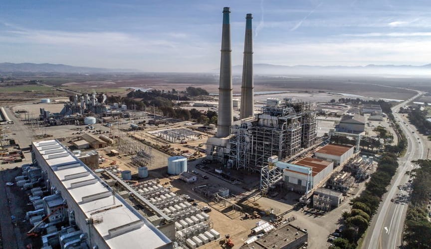 An aerial overhead shot of a large  industrial facility and power plant with two large smokestacks next to a road